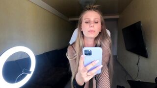 A blonde girl fucks with her phone in her hands