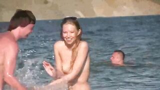 A mature woman sunbathes naked on the beach, showcasing her body