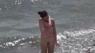 A couple of nudists are having fun on the beach without clothes