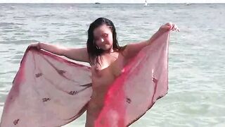 A naked girl is having fun in the sea, showcasing her body