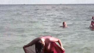 A naked girl is having fun in the sea, showcasing her body