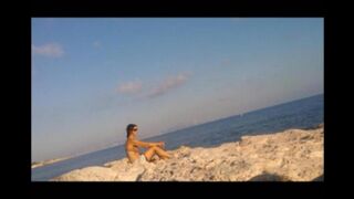 A sexy girl is basking in the sun naked on the beach