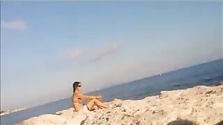 A sexy girl is basking in the sun naked on the beach